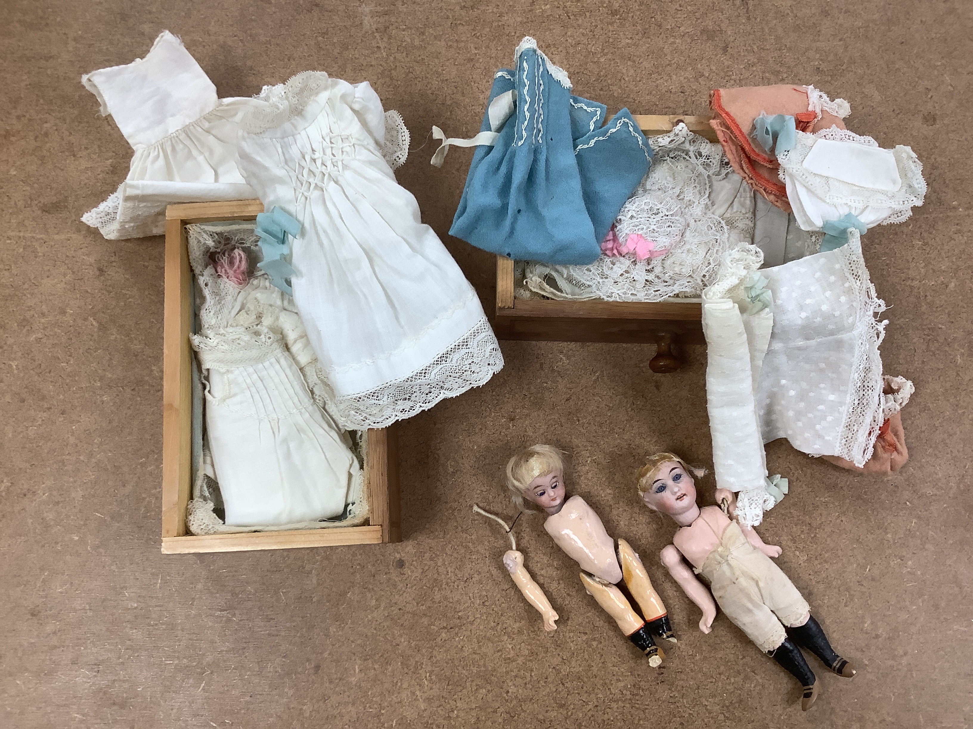 A miniature oak chest of drawers and contents (miniature bisque headed dolls and linen) height 22cm